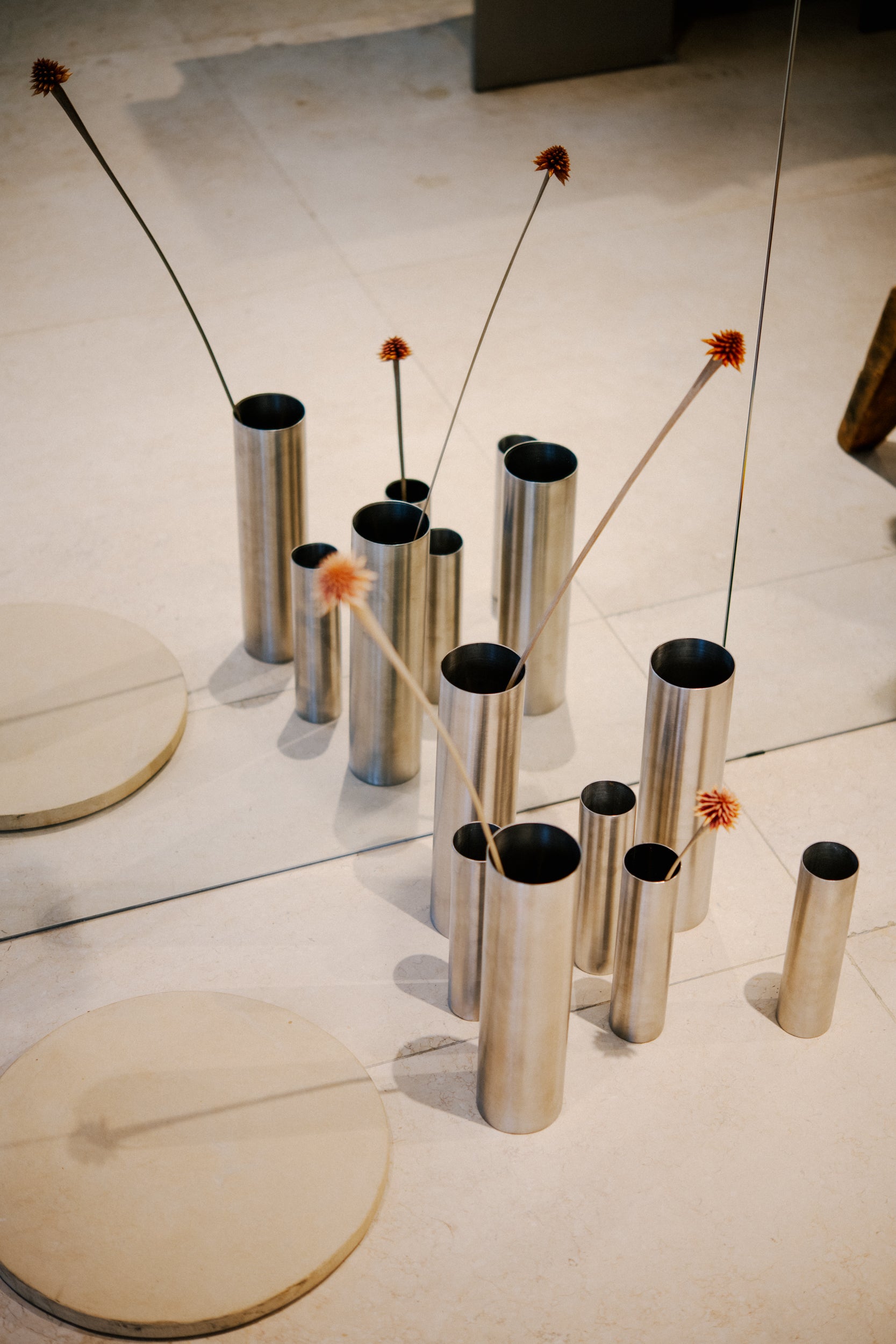 Florero grande. Tiene una tapa perforada que permite sostenerlas en su interior. Fabricado a partir de tubo industrial de acero inoxidable.