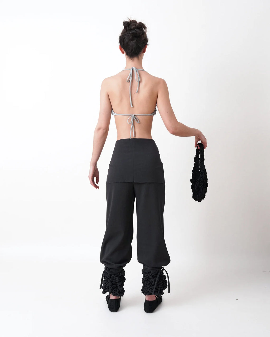 Este es un pantalón que viene con una mini falda adherida y un fruncido libre en la parte final de la bota, acompañado de unas tiras que permiten recoger y anudar y ajustar la bota. Esta es una tela stretch.