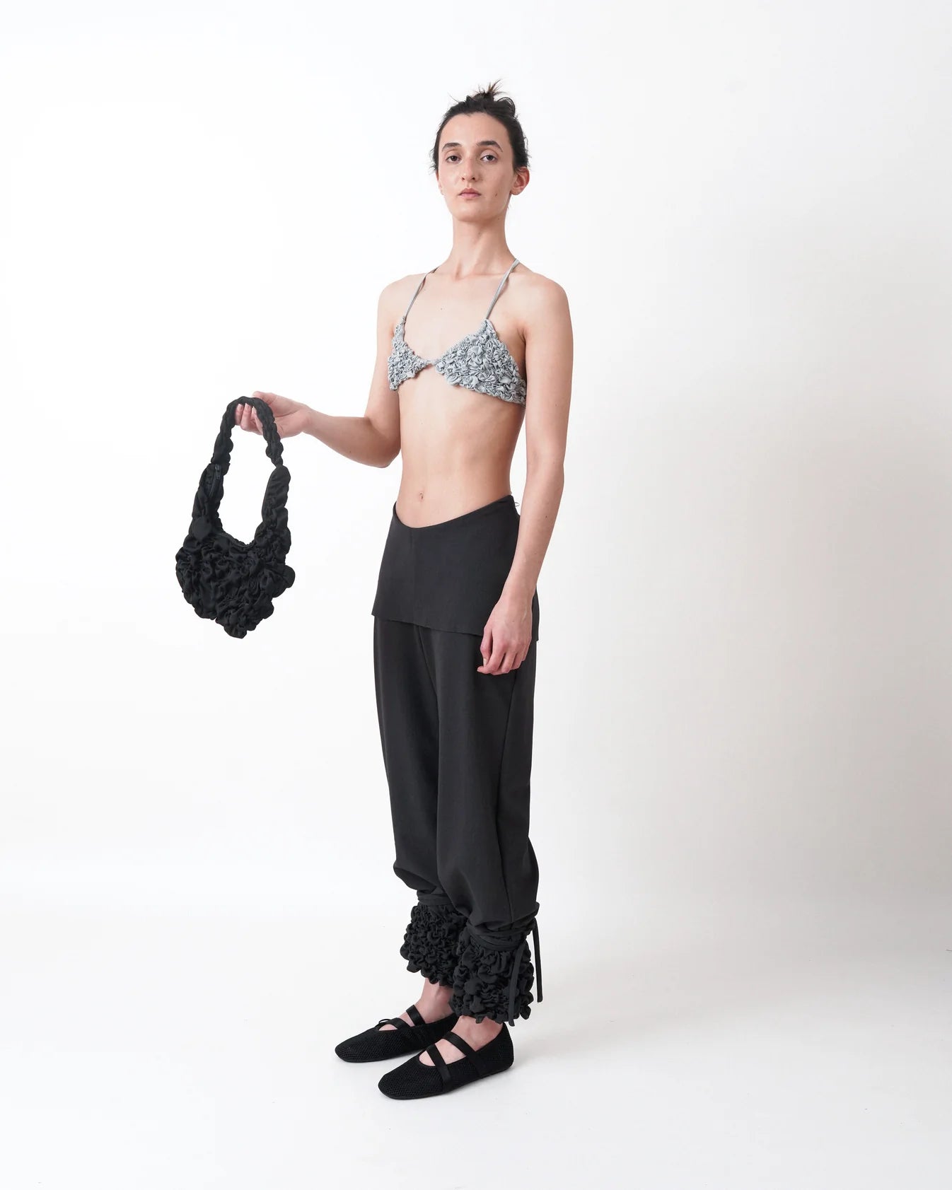 Este es un pantalón que viene con una mini falda adherida y un fruncido libre en la parte final de la bota, acompañado de unas tiras que permiten recoger y anudar y ajustar la bota. Esta es una tela stretch.